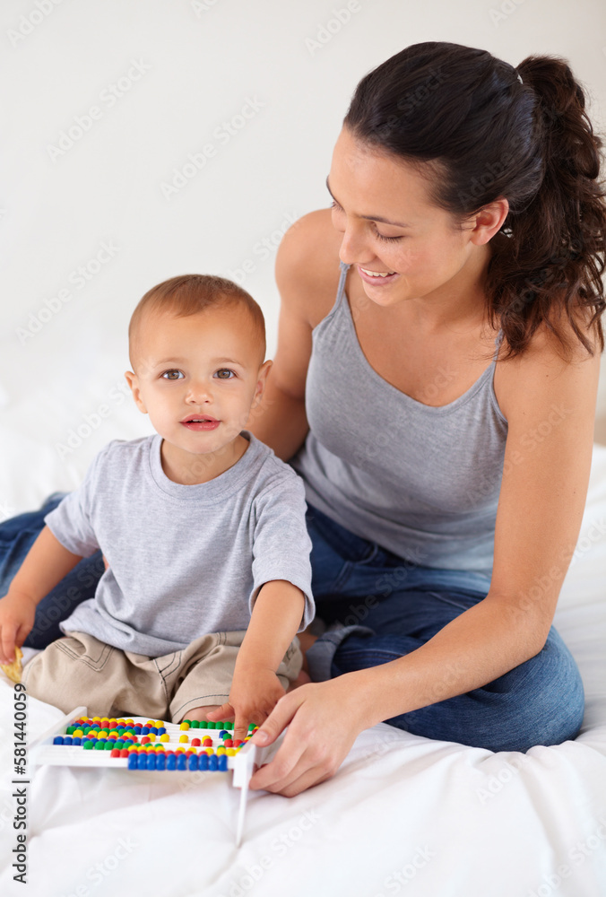 Learning is key to his development. A toddler boy sitting with his mom and playing with an abacus. Learning is key to his development. A toddler boy sitting with his mom and playing with an abacus.