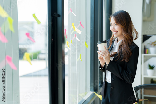 Happy Asian businesswoman in a suit holding a coffee cup Refreshing drink.