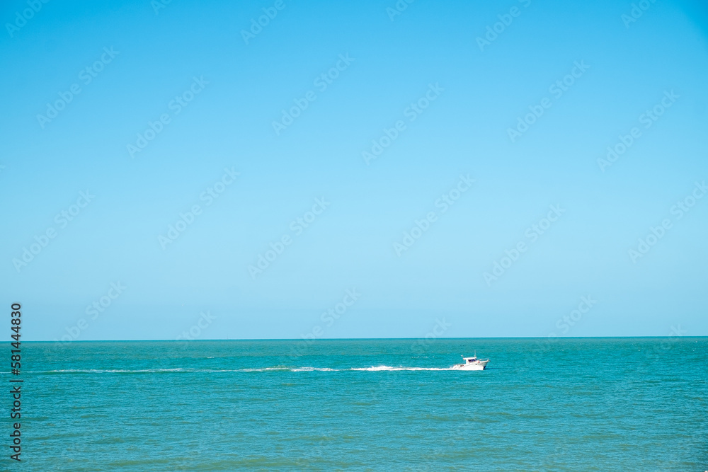 A white yacht moves away from the shore in the blue sea to the horizon. High quality photo