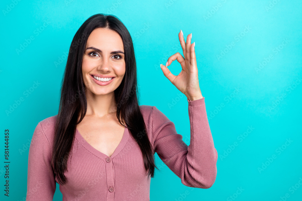 Portrait of positive lovely girl toothy smile hand fingers demonstrate okey symbol isolated on turquoise color background Portrait of positive lovely girl toothy smile hand fingers demonstrate okey symbol isolated on turquoise color background