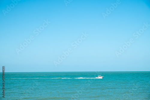 A white yacht moves away from the shore in the blue sea to the horizon. High quality photo