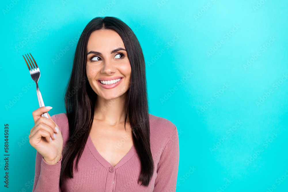 Photo of positive cute person arm hold fork look interested empty space isolated on teal color background Photo of positive cute person arm hold fork look interested empty space isolated on teal color background