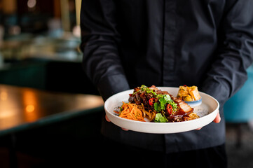 chef hand hold plate whith Stewed pork slice with noodles and vegetables