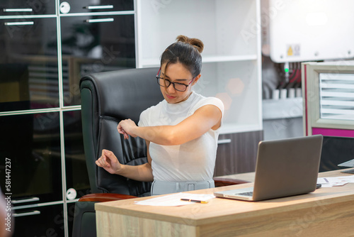 tired asian business woman stretch body. company employee hurt body prevent by stretch. beautiful exhausted young adult female worker person lean and stretching arm reduce pain from office syndrome © tai