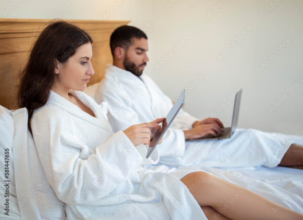 Freelancers Spouses Using Digital Tablet And Laptop Computers In Bedroom Freelancers Spouses Using Digital Tablet And Laptop Computers In Bedroom