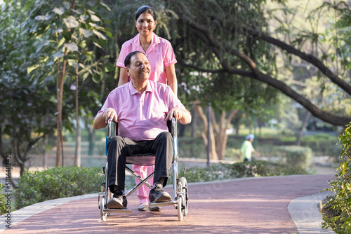 Canvas Print Female nurse with old man in wheelchair admiring view at park