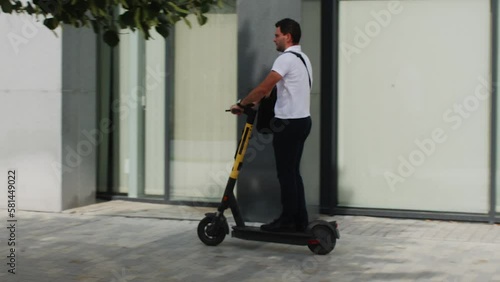 Wallpaper Mural Businessman rides electronic scooter on city street sidewalk near modern building in Summer warm day. New way to move in the urban environment. Eco friendly comfort transport. Ecology transportation. Torontodigital.ca