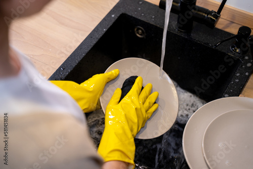 Woman washing dishes in the kitchen. Close up of woman hand. Housewife clean dishes