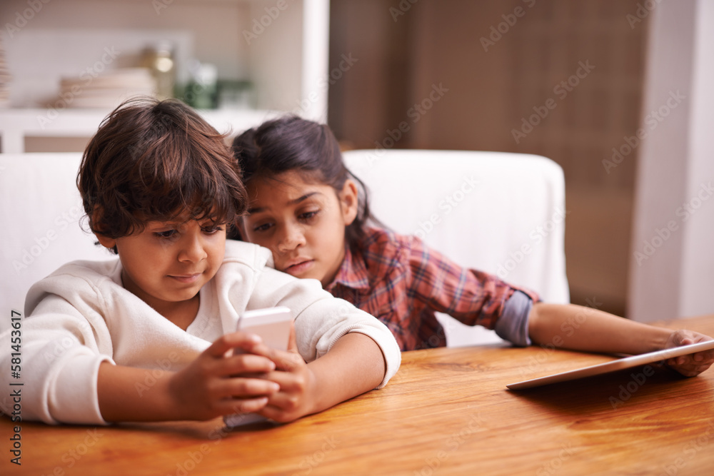 Siblings gone digital. two siblings playing with their digital devices at home. Siblings gone digital. two siblings playing with their digital devices at home.