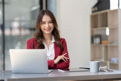 Beautiful Asian businesswoman working on a laptop computer doing financial, accounting analysis, reports, and data at the office.