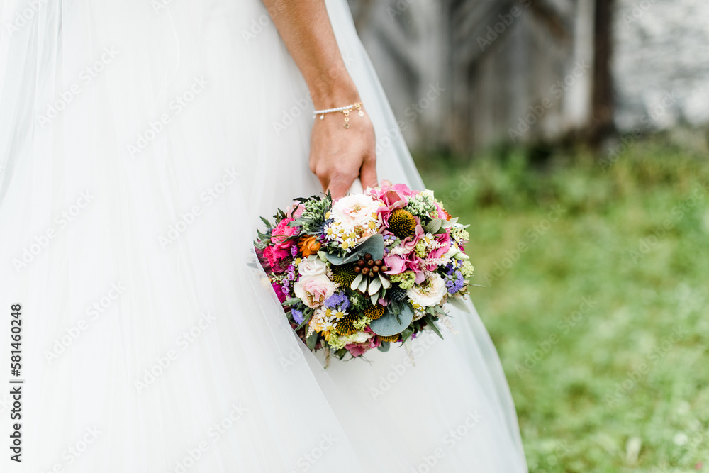 Braut im Brautkleid hält bunten Brautstrauß