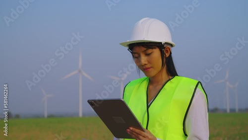 Female engineer checking and survay wind turbine location. She using tablet to check data and work. photo