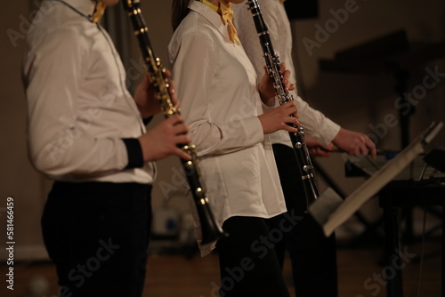 A young musician standing in a band with a wind musical instrument plays the clarinet