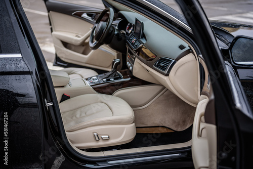 Side view of the open passenger door, mirror, dashboard of car. Right front door. A new modern shiny parked black car. Interior luxury car with tinted glass standing at parking. Modern car exterior.