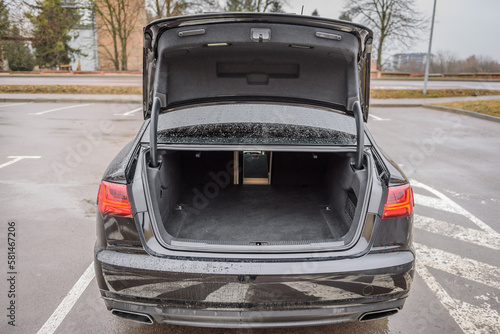 The car is parked with an open trunk. Rear view. Open empty trunk modern sedan car. The car boot is open and ready for luggage loading. Empty space at the boot of Rental car service.