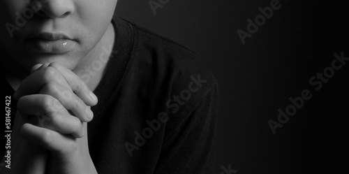 boy praying to God with hands held together with closed eyes on grey black background stock photo  © herlanzer