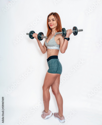 Sexy smiling woman with dumbbell in sports shorts and top. White background. Body positive.