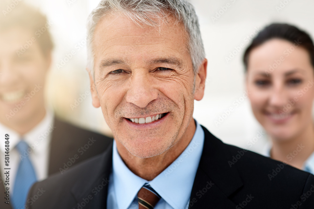 With a great team behind you, anything can happen. Portrait of a mature businessman with colleagues standing in the background. With a great team behind you, anything can happen. Portrait of a mature businessman with colleagues standing in the background.