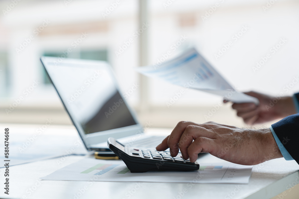 Young businessman analyzing Calculate with investment calculator, income, tax, account from data graph. Financial income in real estate projects View earnings on laptop at office desk. Young businessman analyzing Calculate with investment calculator, income, tax, account from data graph. Financial income in real estate projects View earnings on laptop at office desk.