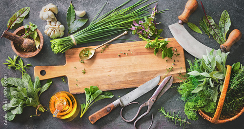 Various fresh herbs from garden with kitchen utensils on rustic table photo