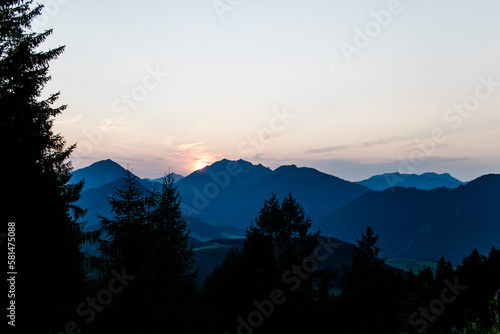 Sonnenuntergang am Berg im Vordergrund mit Bäumen und Wald photo