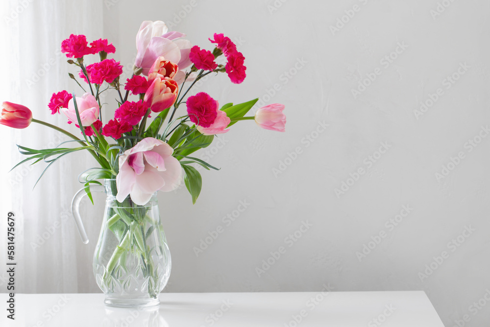 pink spring flowers in glass jug on white background pink spring flowers in glass jug on white background
