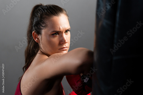 A young woman in a red tracksuit trains in a boxing gym