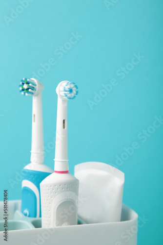 Holder with modern electric toothbrushes on blue background