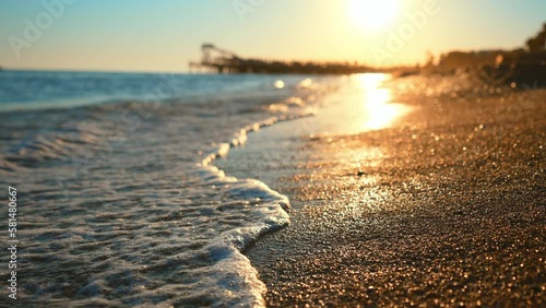Blue sea wave, white foam, golden sand beach, turquoise ocean water and waves from seashore close up. Tourist travel on summer holidays on tropical island. Beauty nature landscape on sun rays sunset.