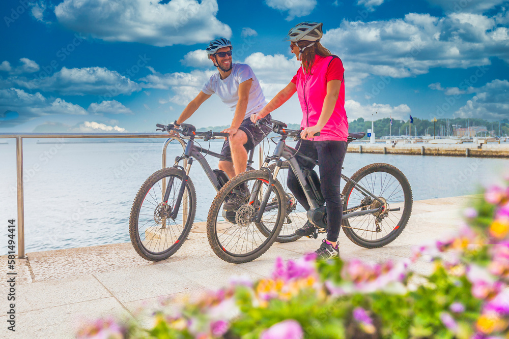 Fototapeta premium Active couple riding an E-Bike during vacations in the south