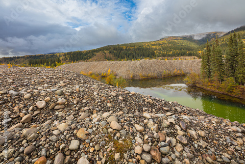 Industrial landscape formed by gold mining operations in the vicinity of Dawson City, Canada; piles with mine tailings left behind by a gold dredge in an autumn forest