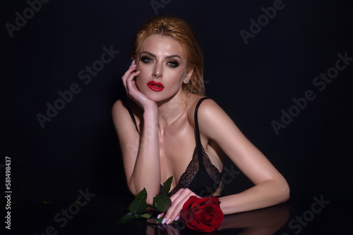 Love and dating. Sexy woman with red rose. Beauty studio portrait. Beautiful model with red rose flower, isolated on black studio background. Romantic dating or proposal.