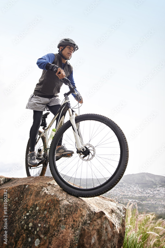 Ready for the down hill. A young man riding a mountain bike with a scenic view in the background.