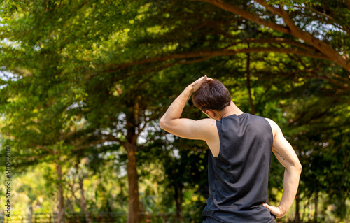 sporty handsome man stretching neck and head after jogging in city public park during summer day, young guy spend quality time on weekend workout outdoor in nature for healthy and active lifestyle