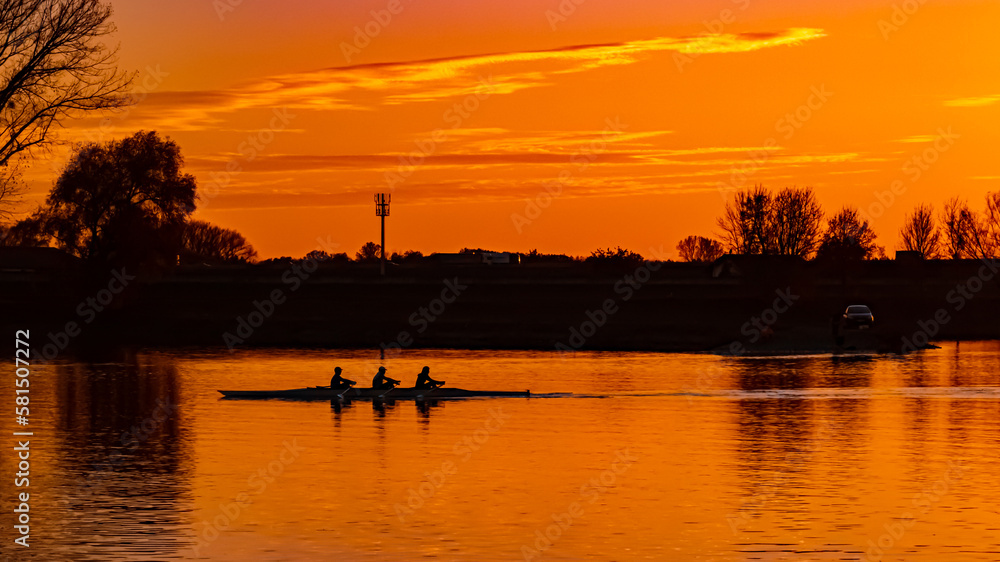 Sunset with reflections and rowers near Metten, Danube, Bavaria, Germany