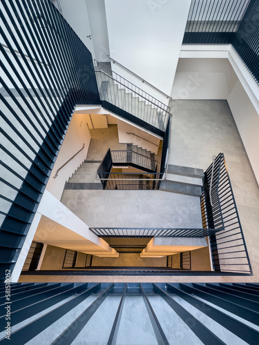 view from above into a stairwell of a multi-storey residential building with black steel railings