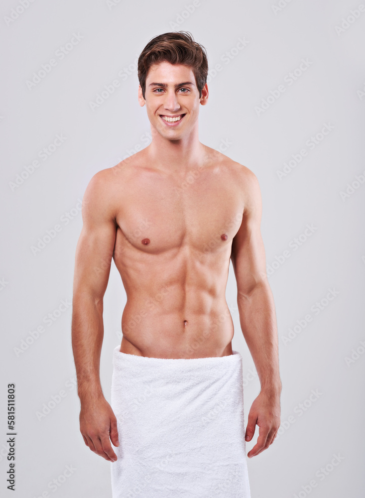 Killer looks and abs. Studio shot of a bare-chested young man with a towel wrapped around his waist.