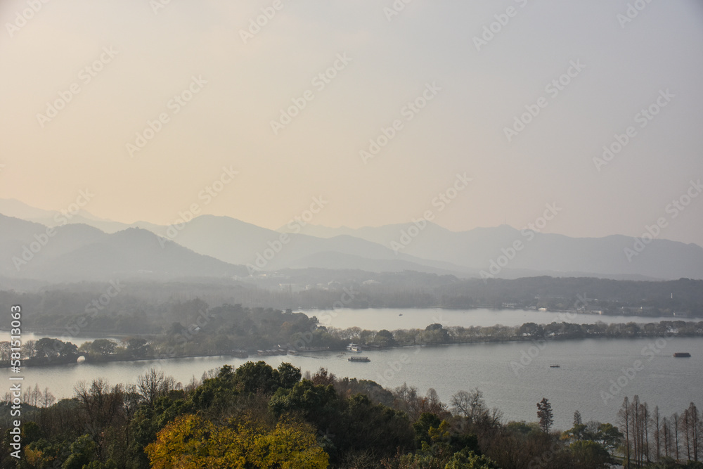 High angle view of the calm seascape and mountains in the cloudy weather. Travel rural scene. West Lake. Popular park of Hangzhou city China.
