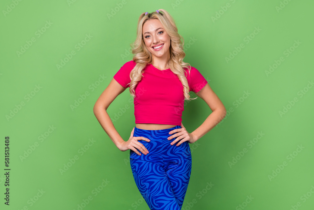 Photo of sweet shiny lady dressed pink t-shirt hands waist smiling isolated green color background Photo of sweet shiny lady dressed pink t-shirt hands waist smiling isolated green color background