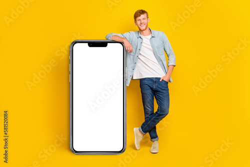 Full size photo of young smart guy hold hand pocket demonstrating new phone collection good software isolated on yellow color background © deagreez