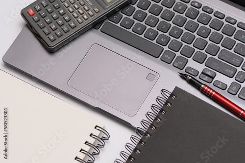 Notes i kalkulator leżące na laptopie na biurku