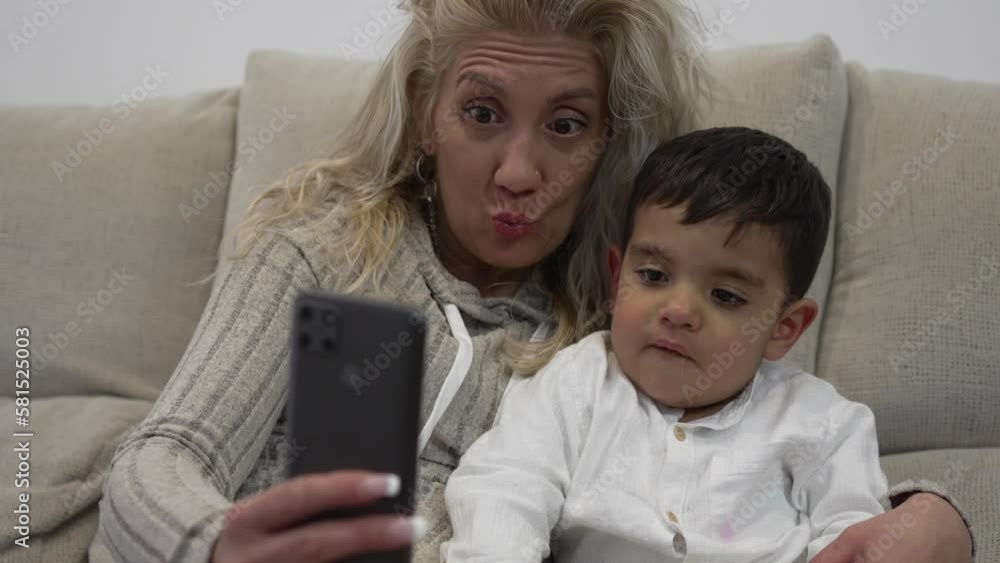Video of a young autistic boy sitting with his blonde mother watching his cell phone and having fun on a video call. Video of a young autistic boy sitting with his blonde mother watching his cell phone and having fun on a video call.