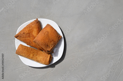 Sri Lankan Chinese Rolls different shape, short eats on gray background. Pan rolls. Authentic street food, vegetable and fish rolls deep fried. Top view, copy space.