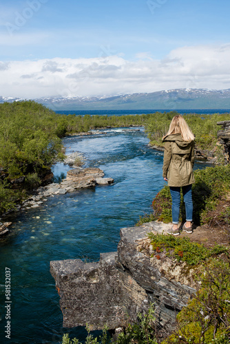 A young woman is enjoying the beautiful natural scenery in the north. Canyon and mountain river. Tourist attraction in Finland. Amazing scenic outdoor view. Travel, adventure, relaxed lifestyle