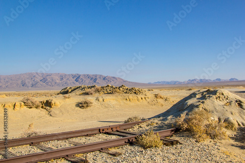 A train in trona pinnacles going through the Mojave desert, eventually intersecting with this empty dirt road. photo