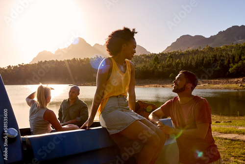 Group Of Friends With Backpacks In Pick Up Truck On Road Trip By Lake At Sunset © Monkey Business
