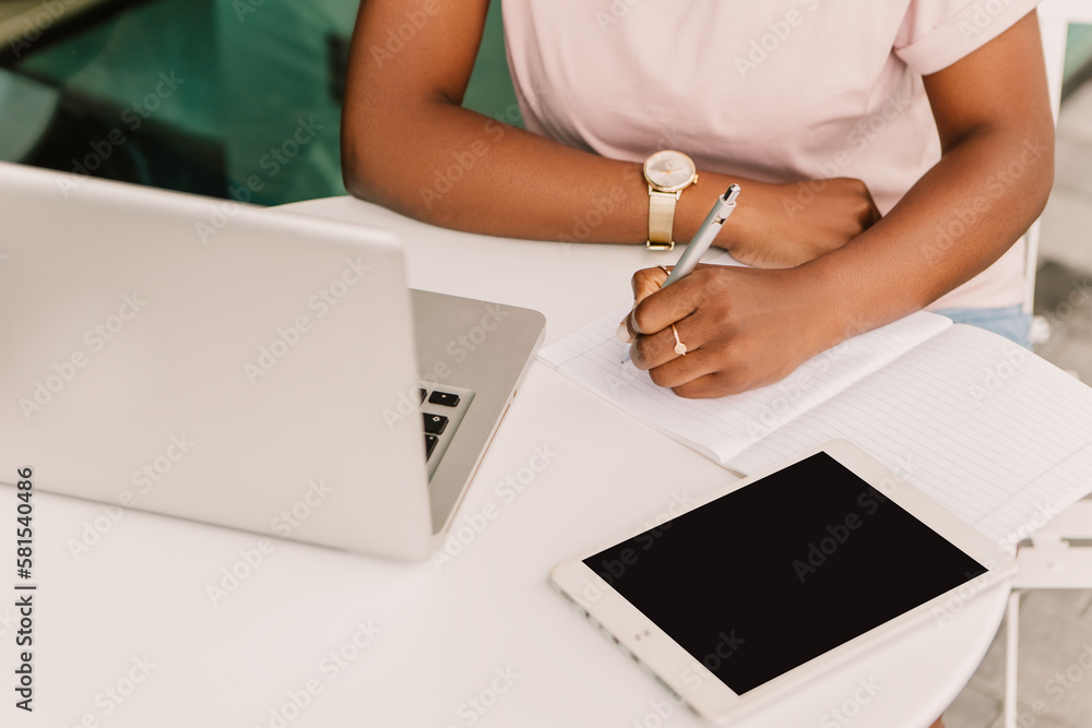 Mock up african american woman hipster sitting outside street cafe using laptop tablet pc gadget, working writing notes text. Young entrepreneur female freelancer high school student businesswoman

