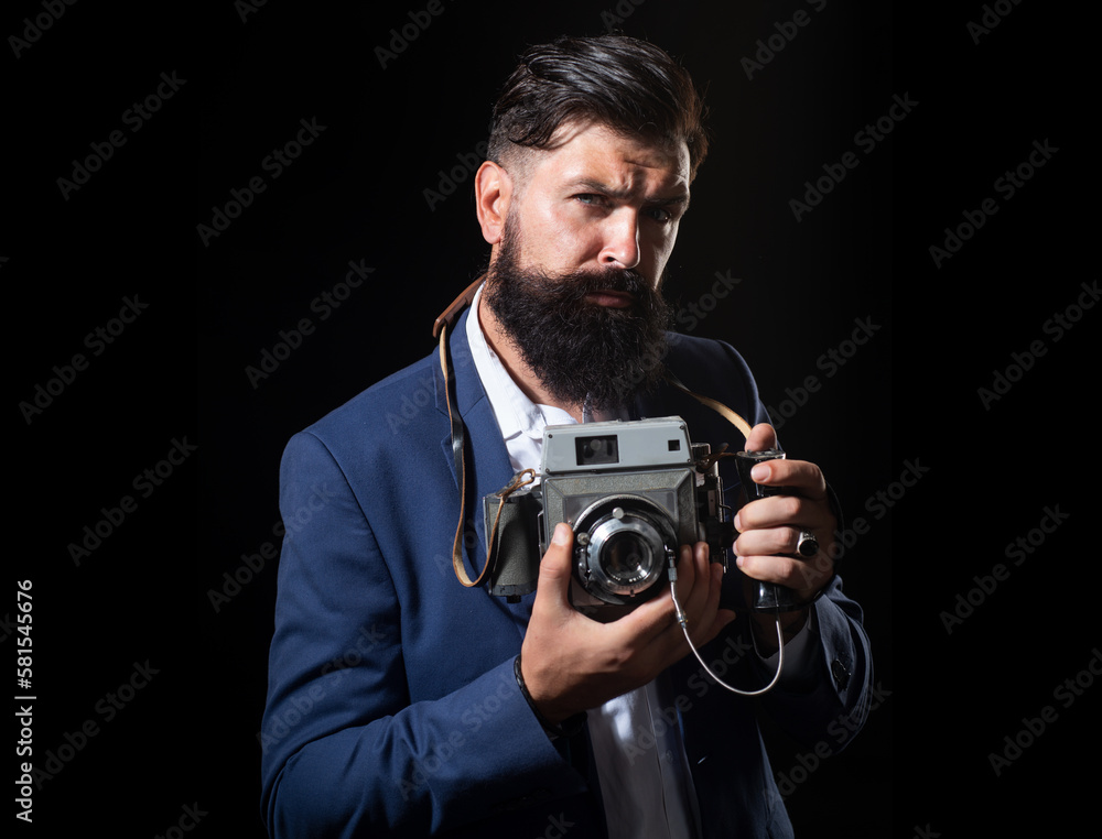 Young man using a professional old camera. Portrait of serious man photographer with vintage retro old film camera isolated on a black background. Young man using a professional old camera. Portrait of serious man photographer with vintage retro old film camera isolated on a black background.