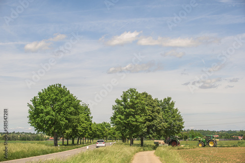Bäuerliche Landschaft mit Bäumen, Landstrasse, Feldweg und Traktoren