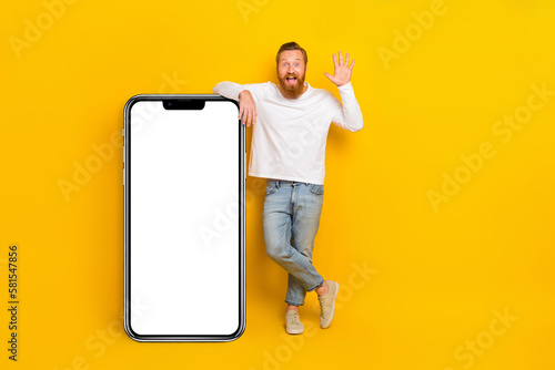 Full body photo of beard man near big telephone wave wear shirt jeans shoes isolated on yellow color background